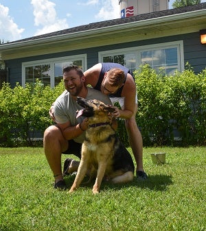 Two men with dog in front yard