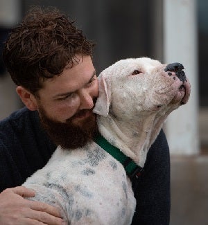 Man snuggling black and white dog