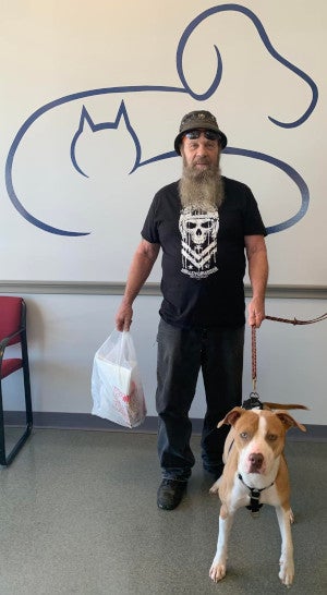 man holding the leash of his newly adopted brown and white dog