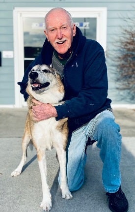 Man kneeling with dog in front of building