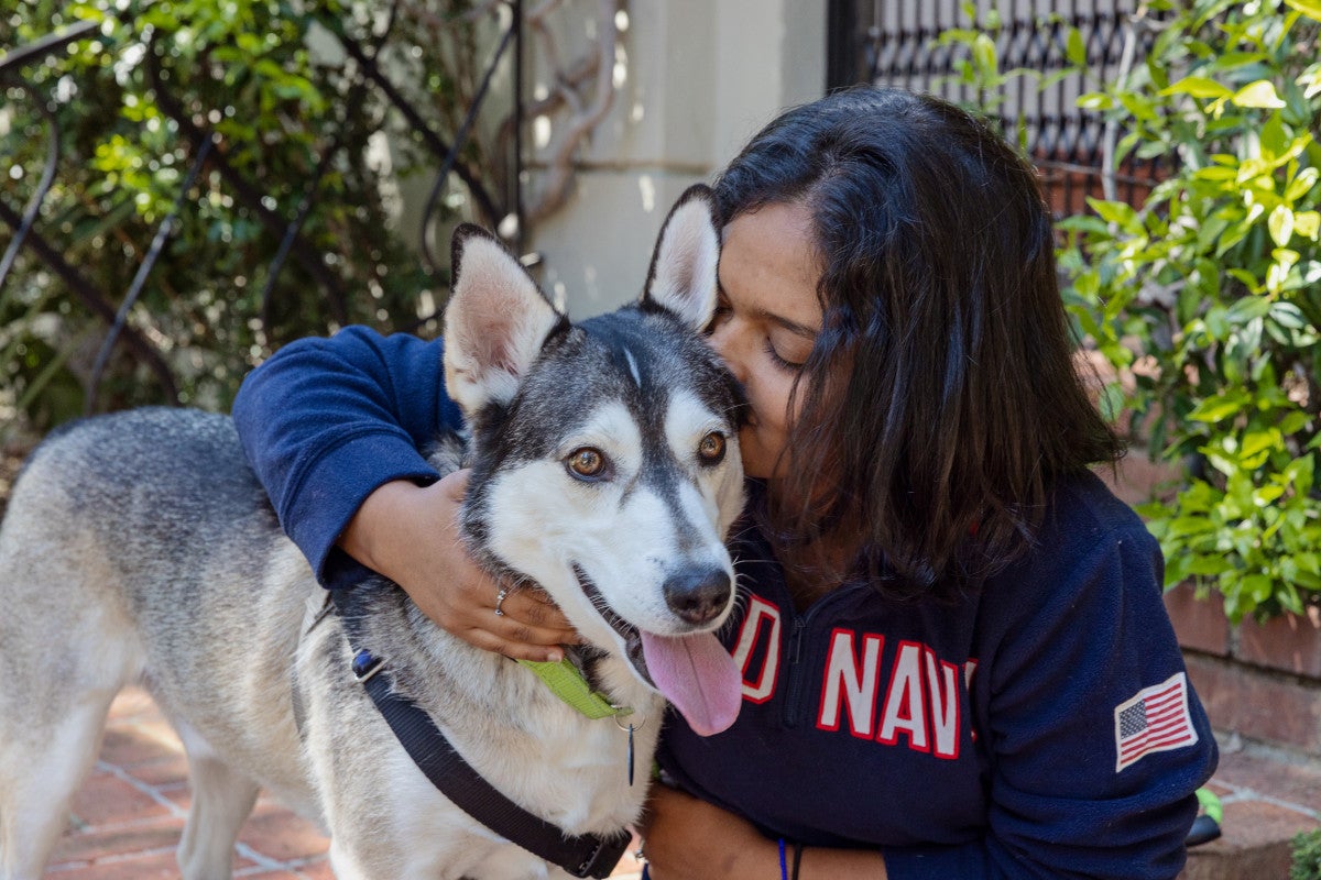 woman kissing a husky dog