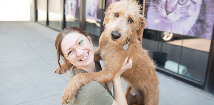 Dog standing up on person wearing green shirt's shoulder